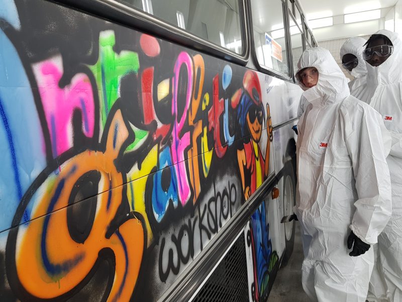 Youth Stand In Front Of A Bus With Graffti
